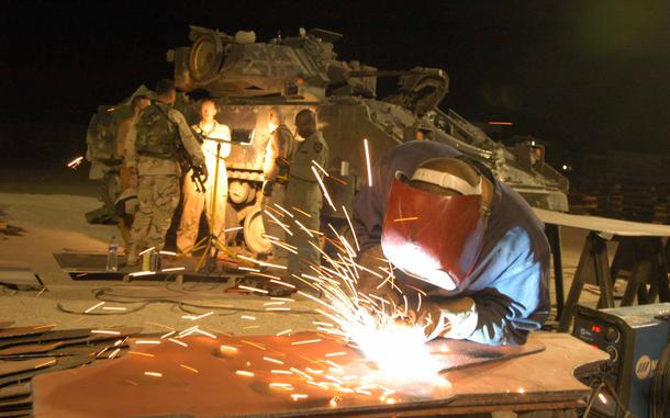 HED: Getting ready for Thunderdome, 2004

Camp Buehring, Kuwait, Aug. 17, 2004: Pfc. Mark Greene of the 699th Maintenance Company, 21, of North Carolina works on an armored door at the Camp Buehring "Mad Max" shop. The shop retro-fits soft-shelled vehicles of troops arriving from Germany, South Korea, Japan and elsewhere with armor, blast-proof windows and air conditioners so they stand a chance against jagged rocks, roadside bombs and the incessant Iraqi heat. 

During a tour of Camp Buehring just a few months later then Defense Secretary Donald Rumsfeld would field questions from Iraq-bound soldiers complaining about being sent into combat without armored vehicles, having to resort to "hillbilly armor," adding scavenged scrap metal and bullet proof glass on to their trucks for protection against roadside bombs in Iraq. 

Caught off guard by the critical questions, Rumsfeld uttered the now famous phrase "You go to war with the army you have, not the army you might want or wish to have at a later time."

Read about the inner workings of the "Mad Max" garage at Camp Buehring and see more photos here. 
https://www.stripes.com/migration/2nd-id-vehicles-are-upgraded-to-survive-rough-traveling-in-iraq-1.23450

META TAGS: Wars on Terror; armor shortage; U.S. Army; Operation Iraqi Freedom; logistics;
