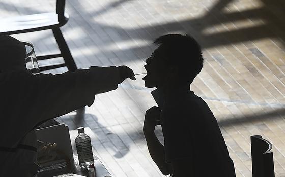 FILE - A medical worker takes a swab sample from a worker of the China Star Optoelectronics Technology (CSOT) company during a round of COVID-19 tests in Wuhan in central China's Hubei province, Aug. 5, 2021. (Chinatopix via AP, File)