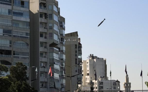 A bomb falls through the air toward a multi-story building.