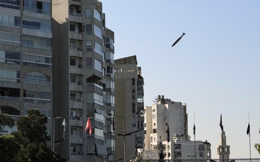 A bomb falls through the air toward a multi-story building.