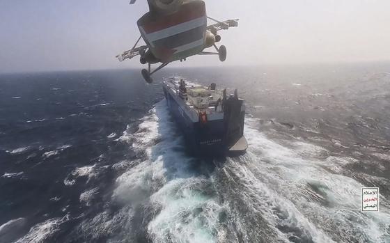 This photo released by the Houthi Media Center shows a Houthi forces helicopter approaching the cargo ship Galaxy Leader on Sunday, Nov. 19, 2023. Yemen's Houthis have seized the ship in the Red Sea off the coast of Yemen after threatening to seize all vessels owned by Israeli companies. (Houthi Media Center via AP)