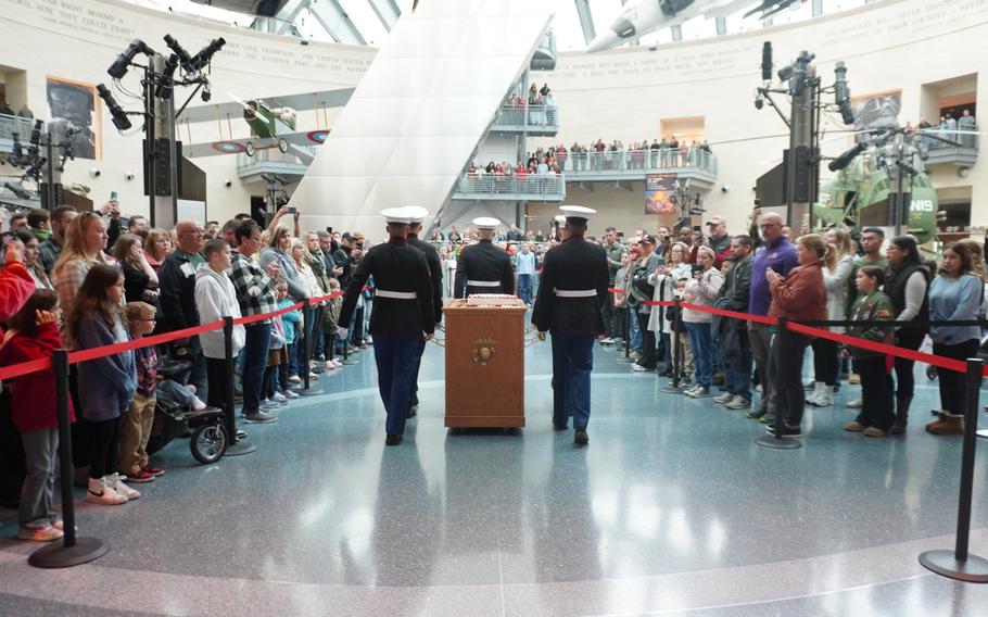 U.S. Marines in dress blues roll the Marine Corps birthday cake through a crowd of people in Leatherneck Gallery