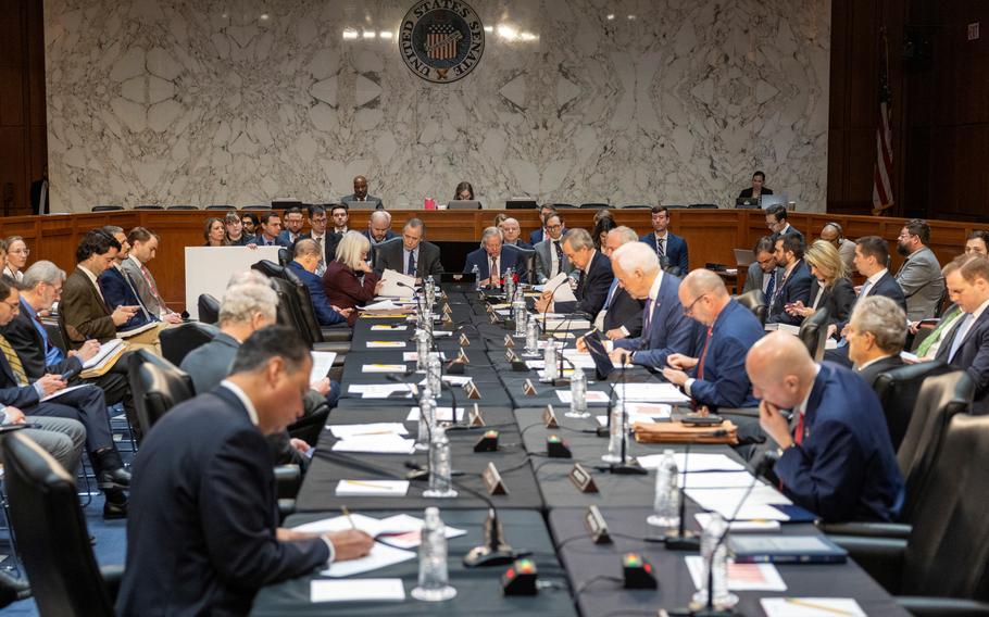 Senators sitting around a table looking at documents.