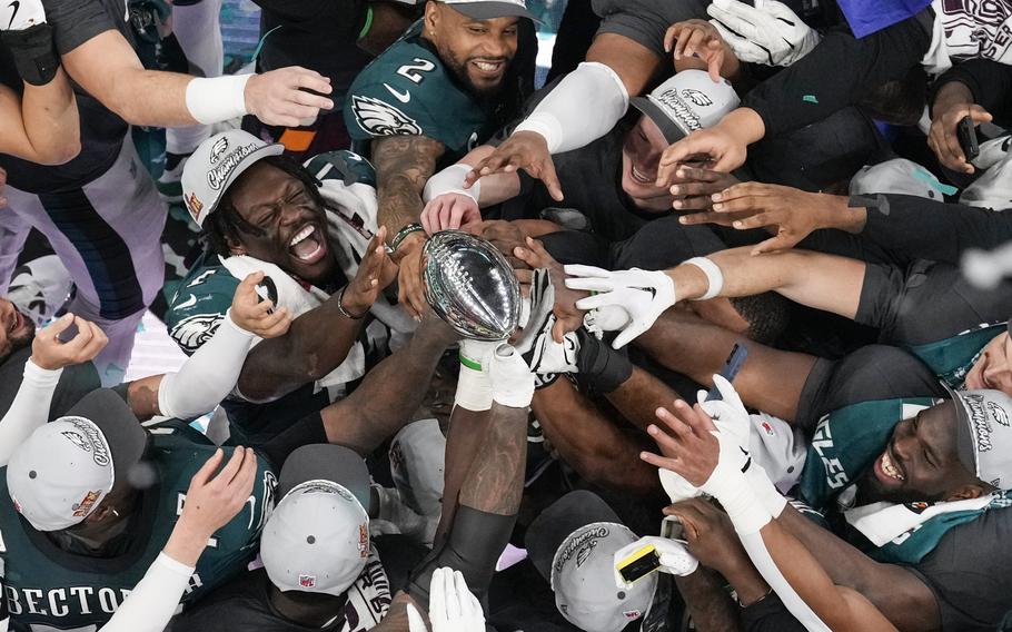 Philadelphia Eagles football players celebrate with the Vince Lombardi Trophy.