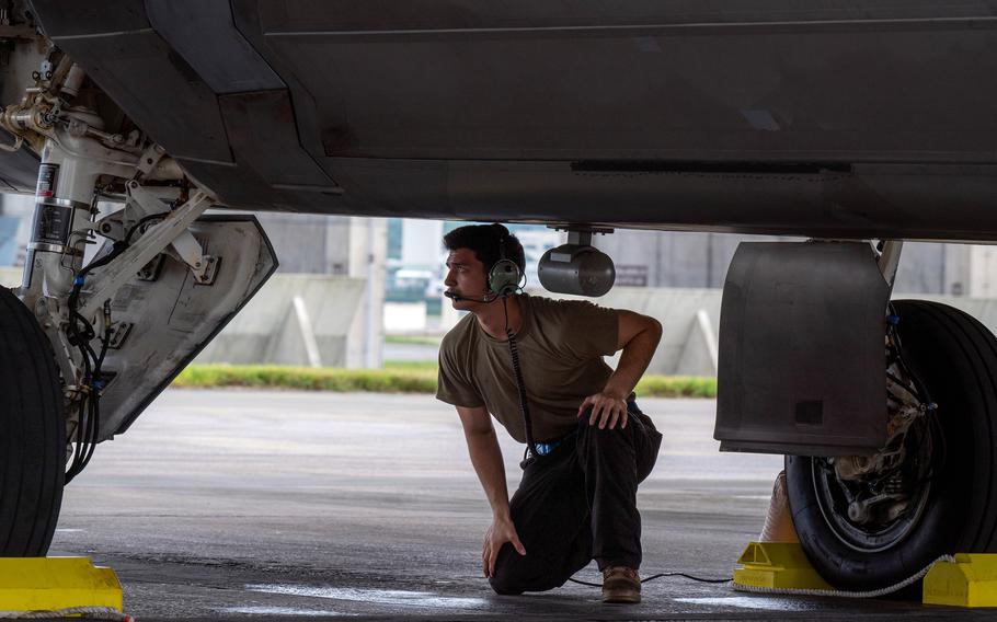 The crew chief kneels beneath an F-22A Raptor.