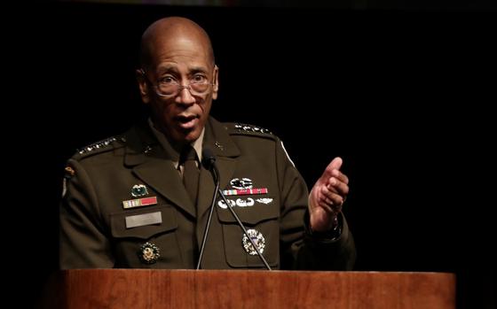 An Army general in dress uniform stands at a podium and speaks into a microphone.