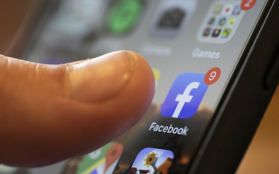 A closeup of an iPhone with a thumb hovering towards the Facebook app.