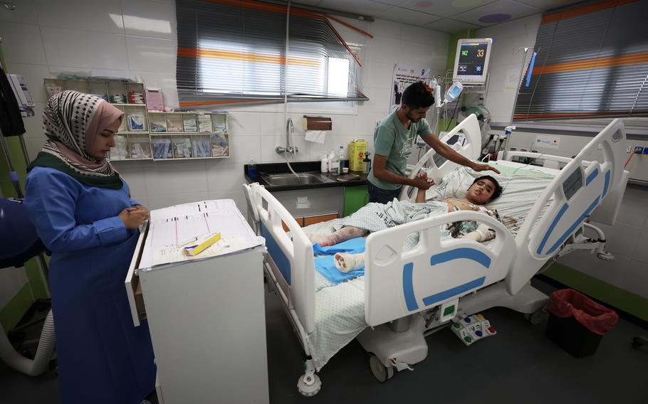 Hamza al-Farra, 11, who was injured in a strike on his family’s home, is comforted by a family member in the pediatric intensive care unit of the Nasser Hospital in Khan Younis on Friday, Oct. 27, 2023.