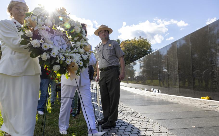 Women carry a wreath of flowers to the Vietnam Veterans Memorial.