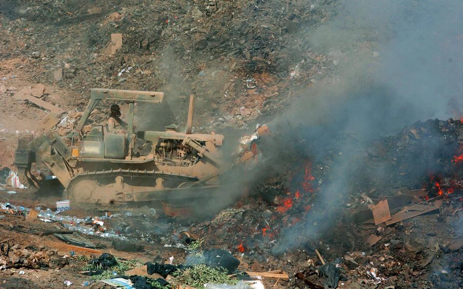 Sgt. Richard Ganske, a soldier with the 84th Combat Engineer Battalion, uses a bulldozer to push refuse into a burn pit in Balad, Iraq, on Sept. 24, 2004.