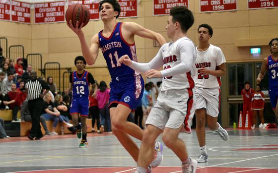 Ramstein's Michael Gonzales travels down the lane while Raider Logan Bell defends during a Jan. 31, 2024, game at Kaiserslautern High School in Kaiserslautern, Germany.