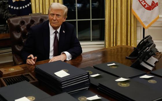 Trump smiles as he signs an executive order in the Oval Office.