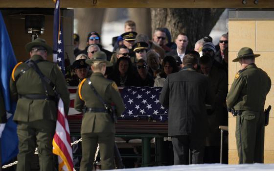 People mourn in front of a casket draped with the American flag.