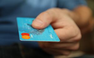 A person holds out a blue debit card.