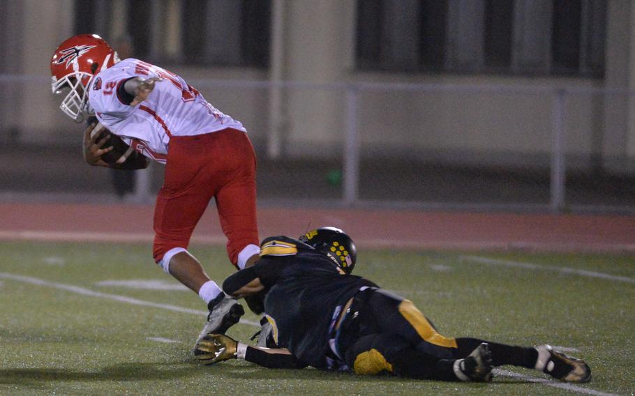 Kinnick quarterback Arashi Blocton slithers free of the grasp of Kadena defender Ethan Ferch. Blocton scored the Red Devils' lone touchdown late in the first half.