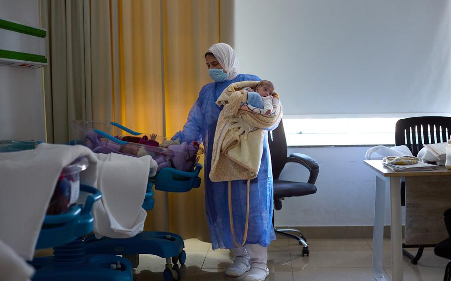 A nurse holds one of Nour al-Banna’s twins while soothing the other.