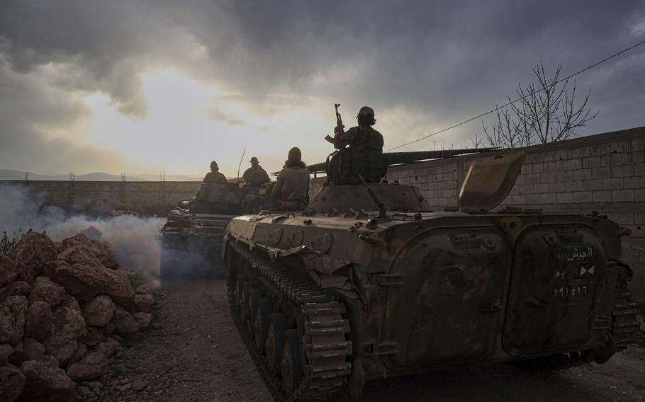 Syrian troops ride military vehicles.