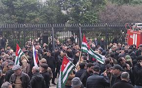 Protesters outside the gates of a parliament building in Georgia’s separatist region of Abkhazia, several of whom are holding the region’s flag.