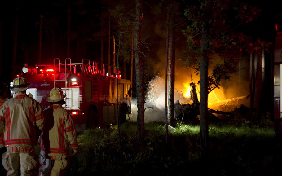 A nightime fire  caused by a CV-22 Osprey crash in a wooded area near Eglin Air Force Base is sprayed with water by firefighters.