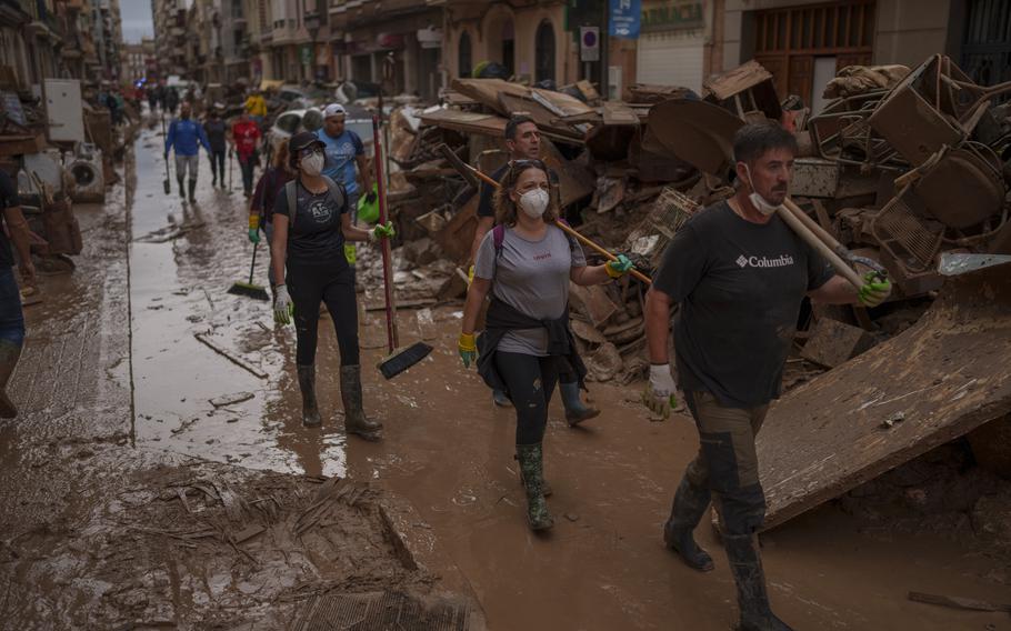 People walk through muddy streets affected by floods in Algemesi, Spain.