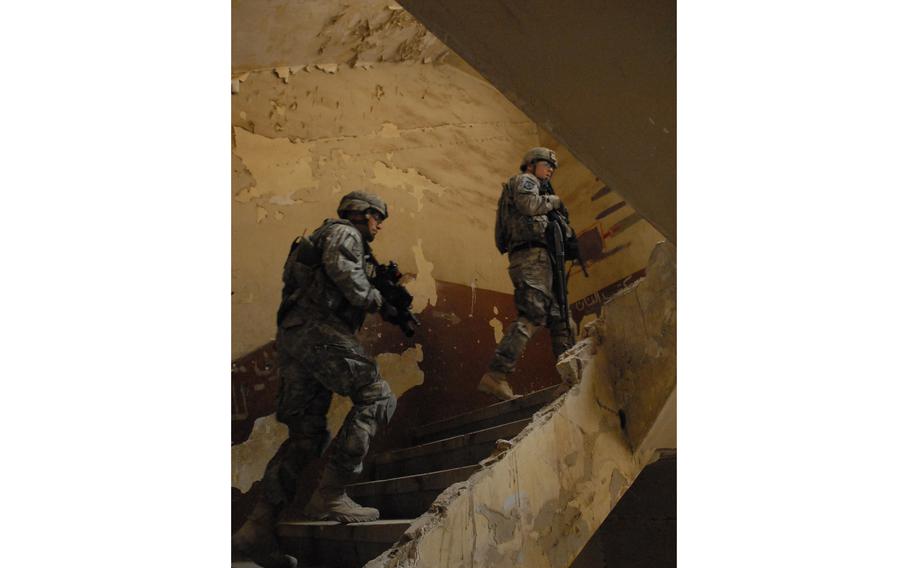 Two soldiers walk up a flight of stairs