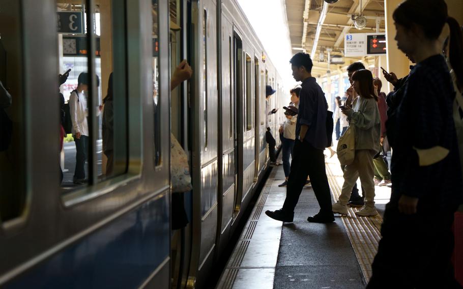 Commuters board a train in Tokyo, Thursday, Oct. 19, 2023.