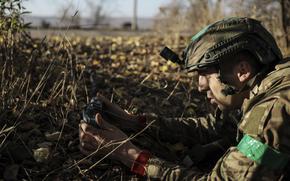 A Ukrainian service member in uniform holds a landmine along the front line near Chasiv Yar town .