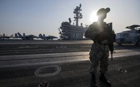 A sailor stands watch on the flight deck of the aircraft carrier USS Carl Vinson as the ship departs Laem Chabang, Thailand, Jan. 31, 2025.