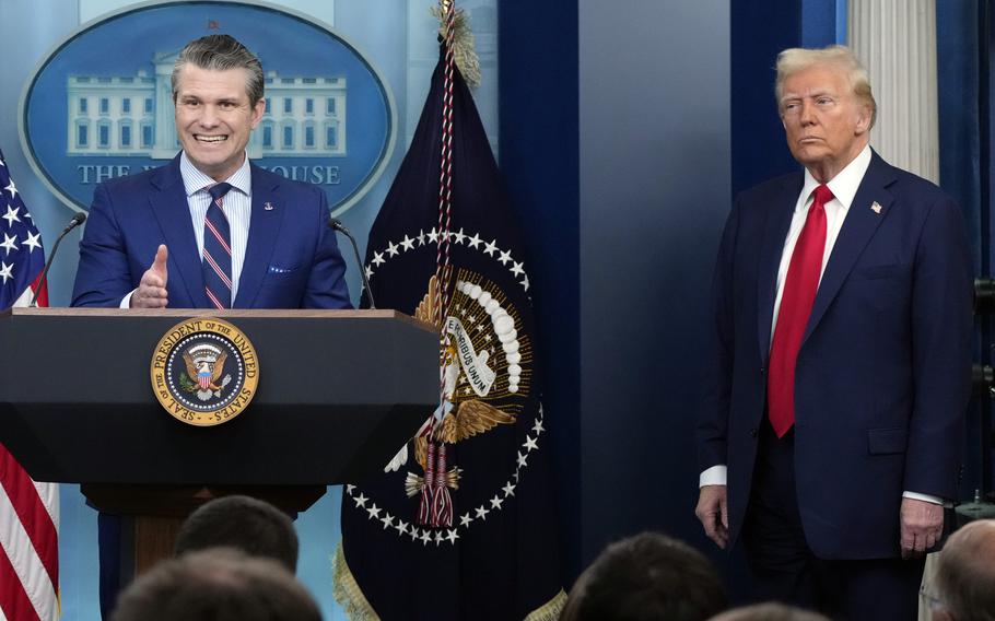 Pete Hegseht stands at a podium and speaks into microphones while Donald Trump stands to the side.