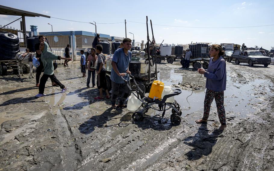 Palestinians gather to fill water jugs at a makeshift tent camp