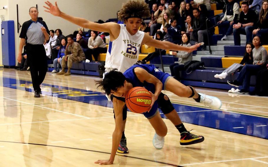 St. Mary’s Max Wahba stumbles in front of Yokota’s Braedon Raybon during Thursday’s Kanto Plain boys basketball game. The Titans won 67-63 in a matchup of last year’s Far East Divisions I and II tournament champions.