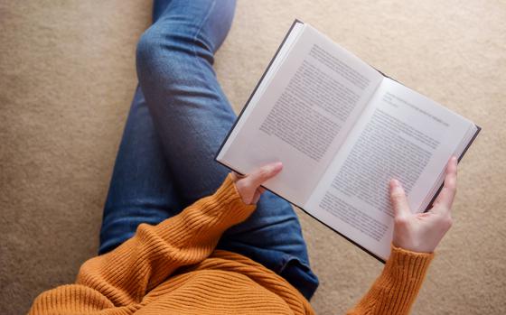 Young Woman Relaxing by Book in Cozy House, Sit on the Floor, Top View