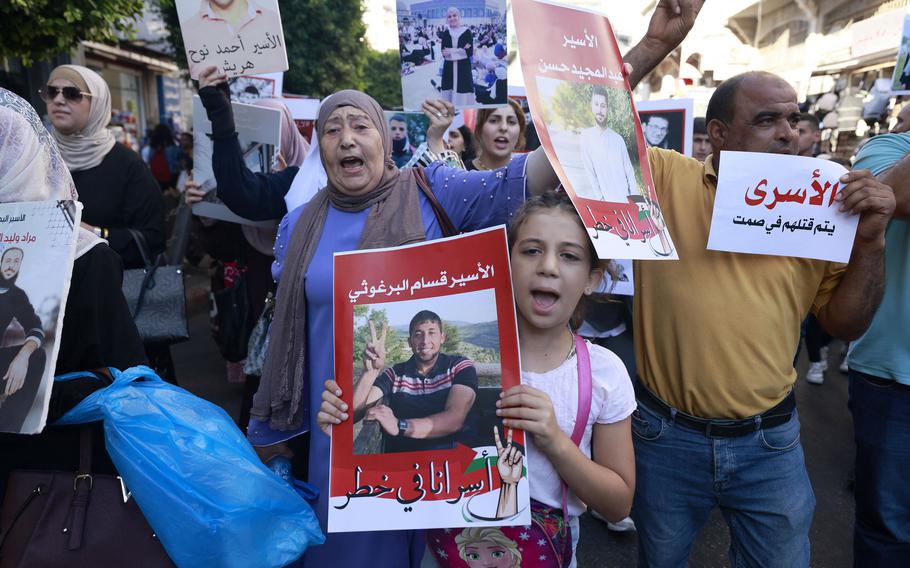 Palestinians some holding images of relatives held in Israeli jails protest calling for their release at the Duwar al-Manara in central Ramallah, in the Israeli occupied West Bank on July 21, 2024. 