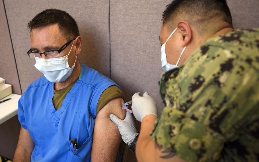 A Navy hospital corpsman administers a COVID-19 vaccine to a fellow medical worker early this year at Naval Base Guam. 