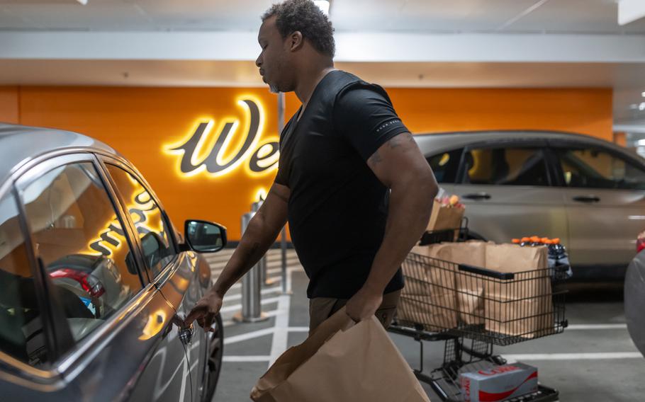 Larry Askew loads his car with an Instacart order. He sticks with Wegmans because its layout rarely changes, allowing him to keep his speed rating high.