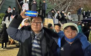 A man waves his phone that displays “Arrest Yoon Suk Yeol” outside of the gates to the National Assembly in Seoul, South Korea, early Dec. 4, 2024.