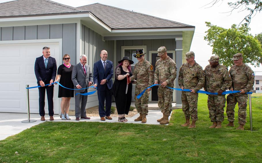 Cavalry Family Housing staff, Lendlease management, and III Armored Corps and Fort Cavazos leaders watch as Allison and Spc. Grant Boshaw of 1st Cavalry Division cut a ribbon June 16, 2023, outside their new home at the Texas Army post. The Boshaw family is the first to receive the keys to a new home.