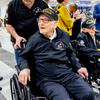 Two military veterans in wheelchairs are greeted at the airport.