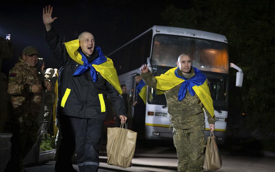 In this photo provided by the Press Service of the President of Ukraine on Oct. 19, 2024, Ukrainian servicemen shout, “Glory to Ukraine,” with National flags after returning from captivity during a POWs exchange in an undisclosed location, Ukraine. 