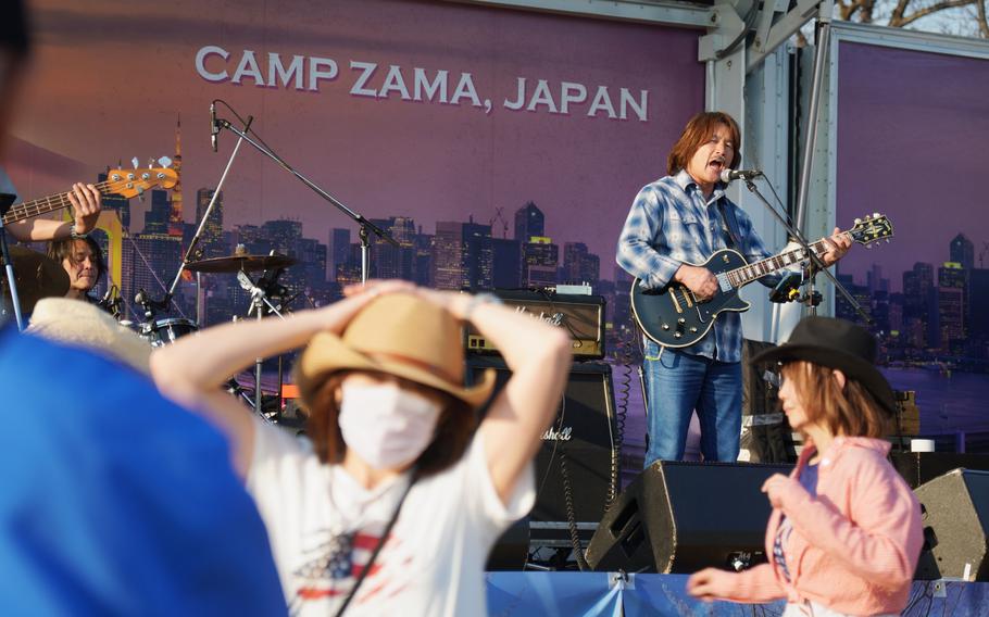 A band plays on stage in front of a festival crowd.