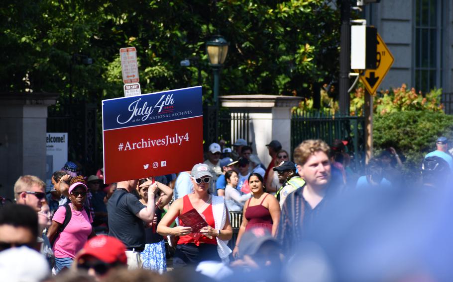 A member of the National Archives event staff carries a sign through a gathering crowd on July 4, 2024.