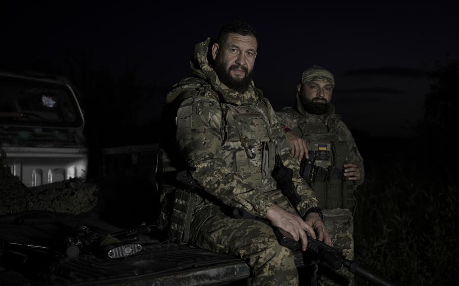 Andrii Shcherbyna, 42, and Oleh Kushnerov, 36, sit on the bed of their truck after returning from a mission near Vovchansk on June 27. 