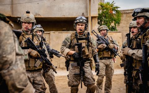 Men in military fatigues standing around with rifles.