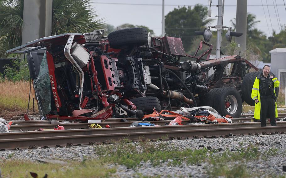 A damaged fire truck is on its side after colliding with a train in downtown Delray Beach, Fla.