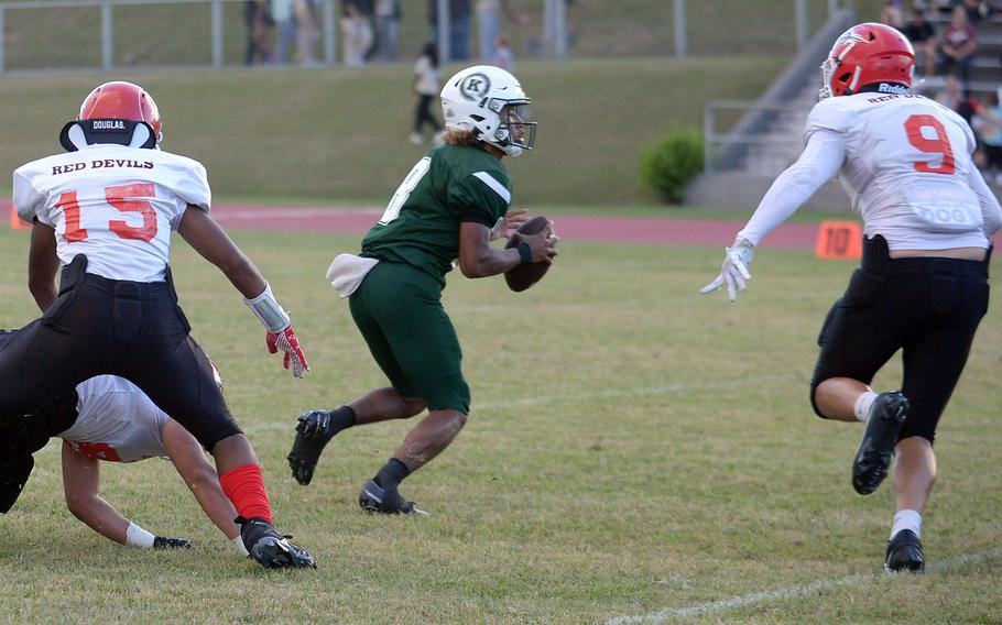 Kubasaki quarterback Trajon Weaver finds himself under pressure from Nile C. Kinnick's Marico Myhand and Kahlil Busscher.