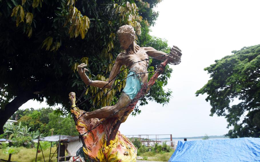 A statue of an emaciated man tangled in barbed wire with flames at his feet.