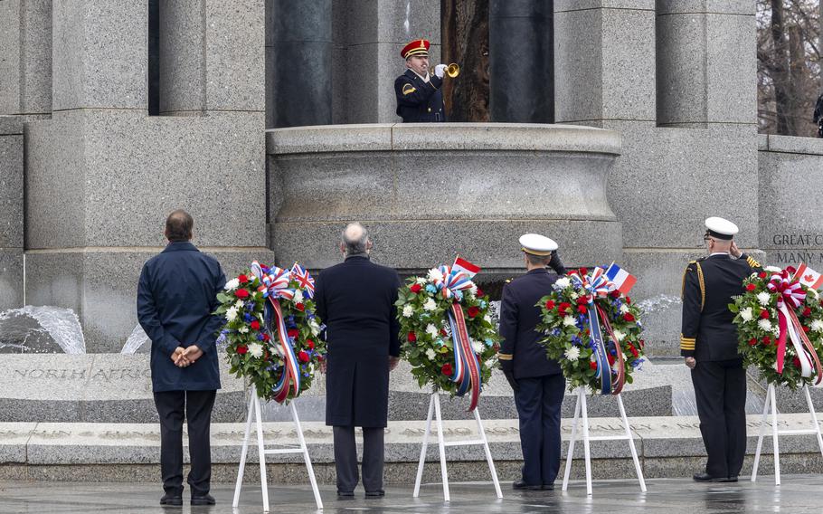 Troops and officials watch as a bugler plays taps.