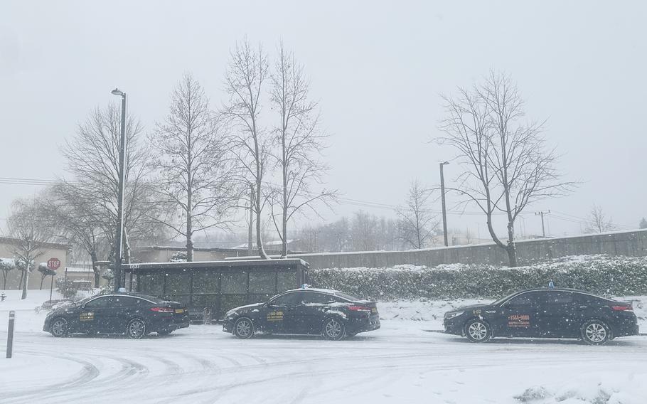 A line of black Taxis wait in the snow.