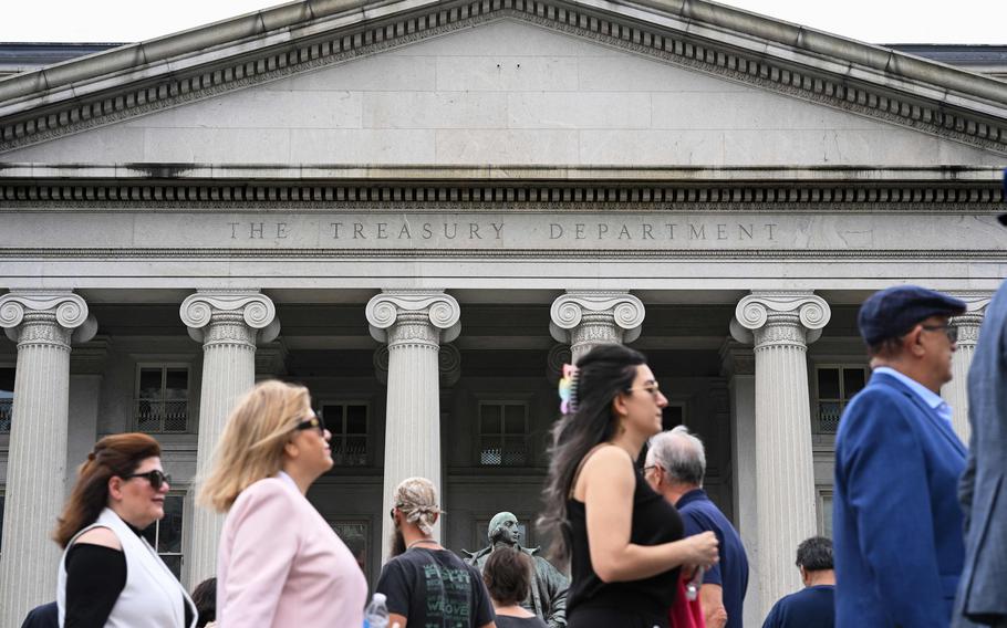 Passers-by in front of the a building that reads “The Treasury Department.”