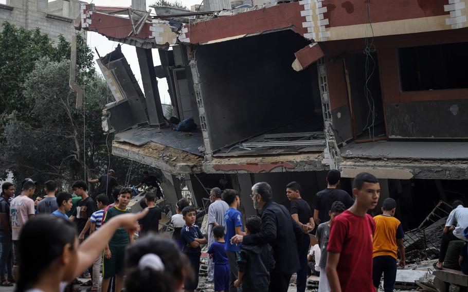 Palestinian residents survey the damage to a destroyed building following Israeli airstrikes overnight in Khan Younis, southern Gaza, on Oct. 9, 2023.